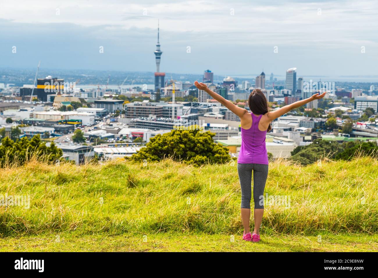 Blick auf die Skyline von Auckland vom Mount Eden of Sky Tower, Neuseeland. Glückliche Frau mit den Armen in Freiheit und Glück auf dem Gipfel des Mt Eden Stadtparks Stockfoto