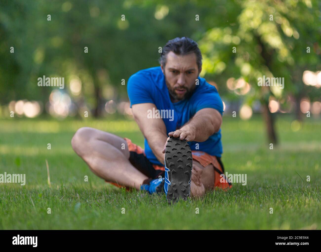 Mann, der sich nach dem Joggen dehnt. Das Konzept eines aktiven Lebensstils und eines gesunden Lebensstils im Alter nach 40 Jahren. Konzentrieren Sie sich auf die Füße. Stockfoto