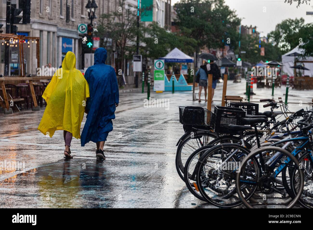 Montreal, CA - 30. Juli 2020: Menschen auf der Mont-Royal Avenue tragen Ponchos bei Regen und Sturm Stockfoto
