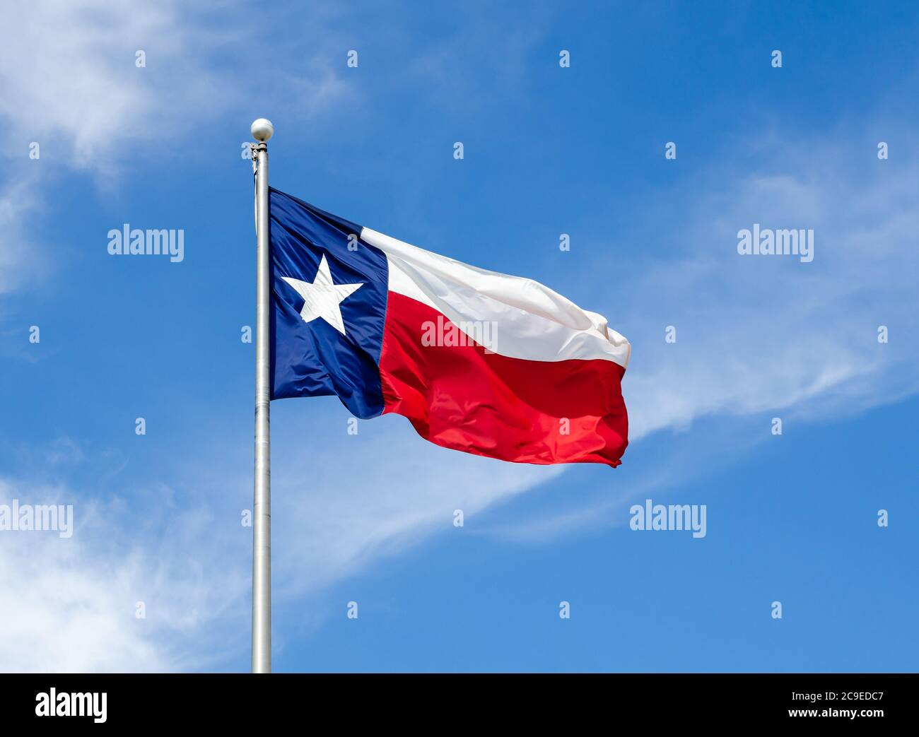Texas State Flagge auf der Stange winkt im Flügel gegen blauen Himmel und weißen Wolken Stockfoto