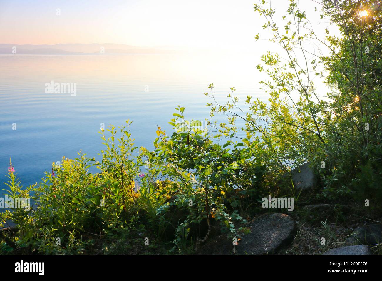 Morgendämmerung über der Wasseroberfläche des Sees. Ruhiges, klares Wasser. Turgoyak, Russland. Stockfoto