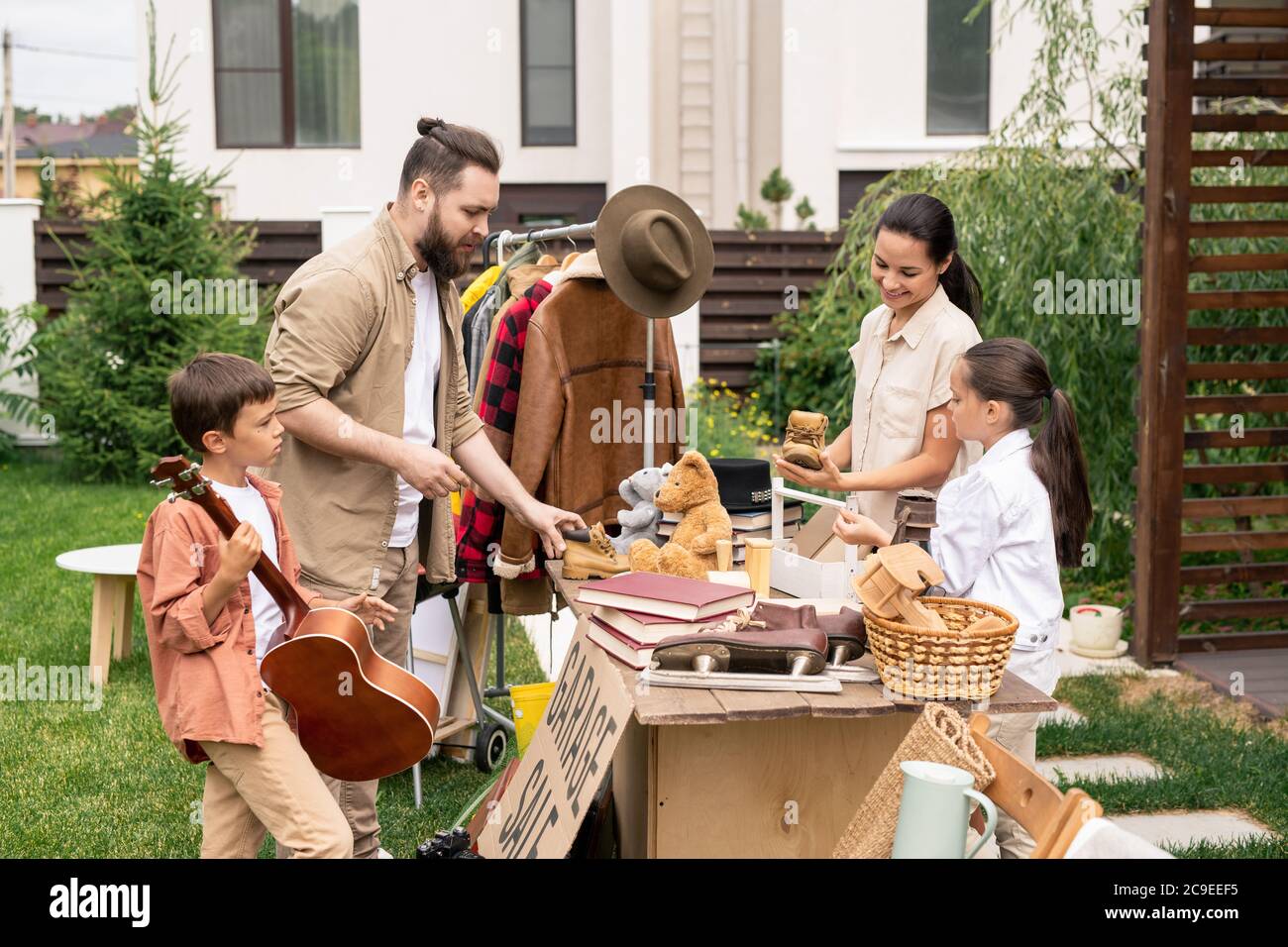 Freundliche junge Familie, die am Tisch im Hinterhof steht und Sachen für den Garagenverkauf verpackt Stockfoto