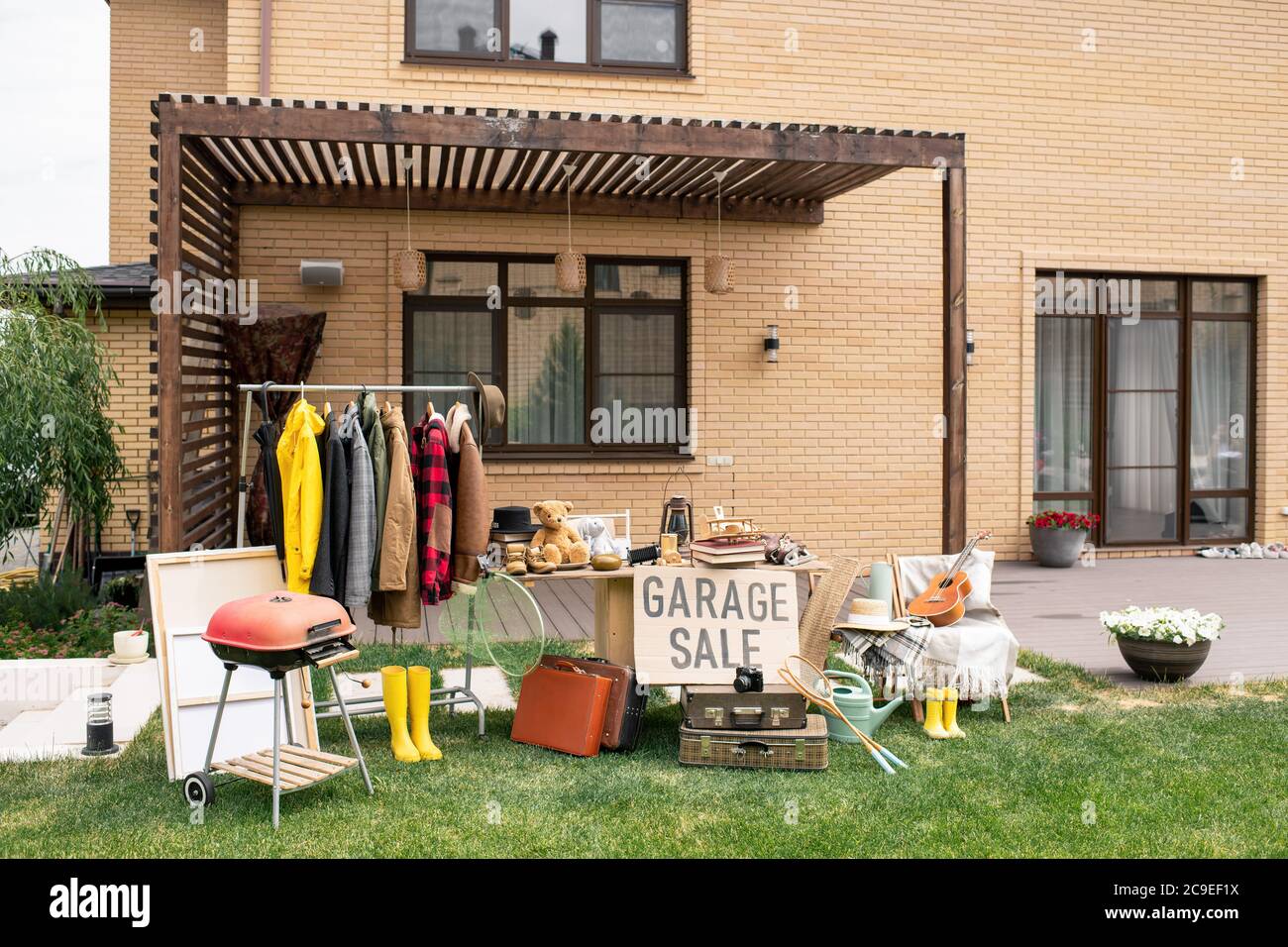 Garage Verkauf Zeichen am Tisch mit einzigartigen Waren im Hinterhof des schönen Backsteinhaus platziert Stockfoto