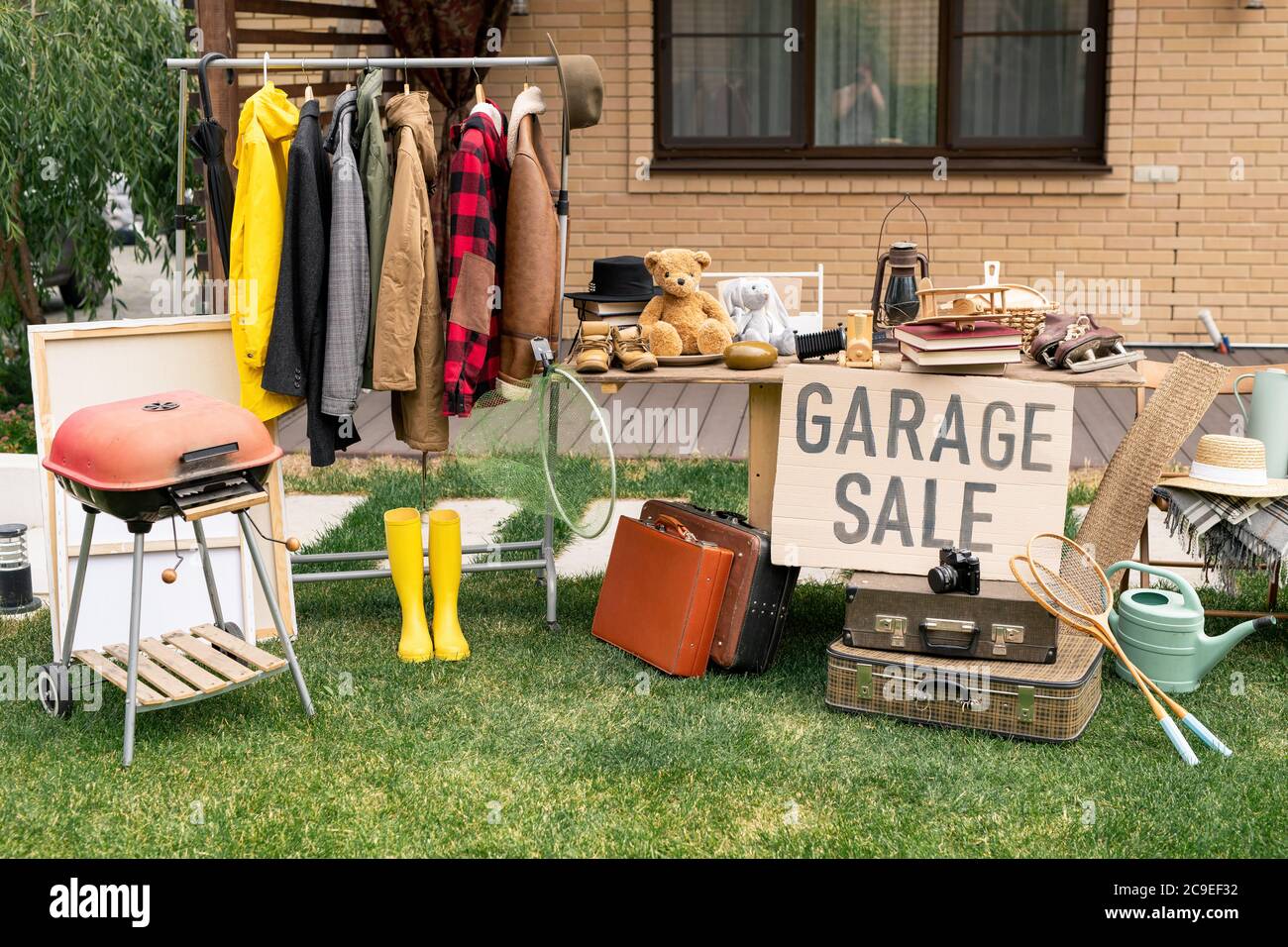 Kleiderständer, altmodische Koffer, Gartengeräte und Innenausstattungen, die auf dem Garagenmarkt im Hinterhof verkauft werden Stockfoto