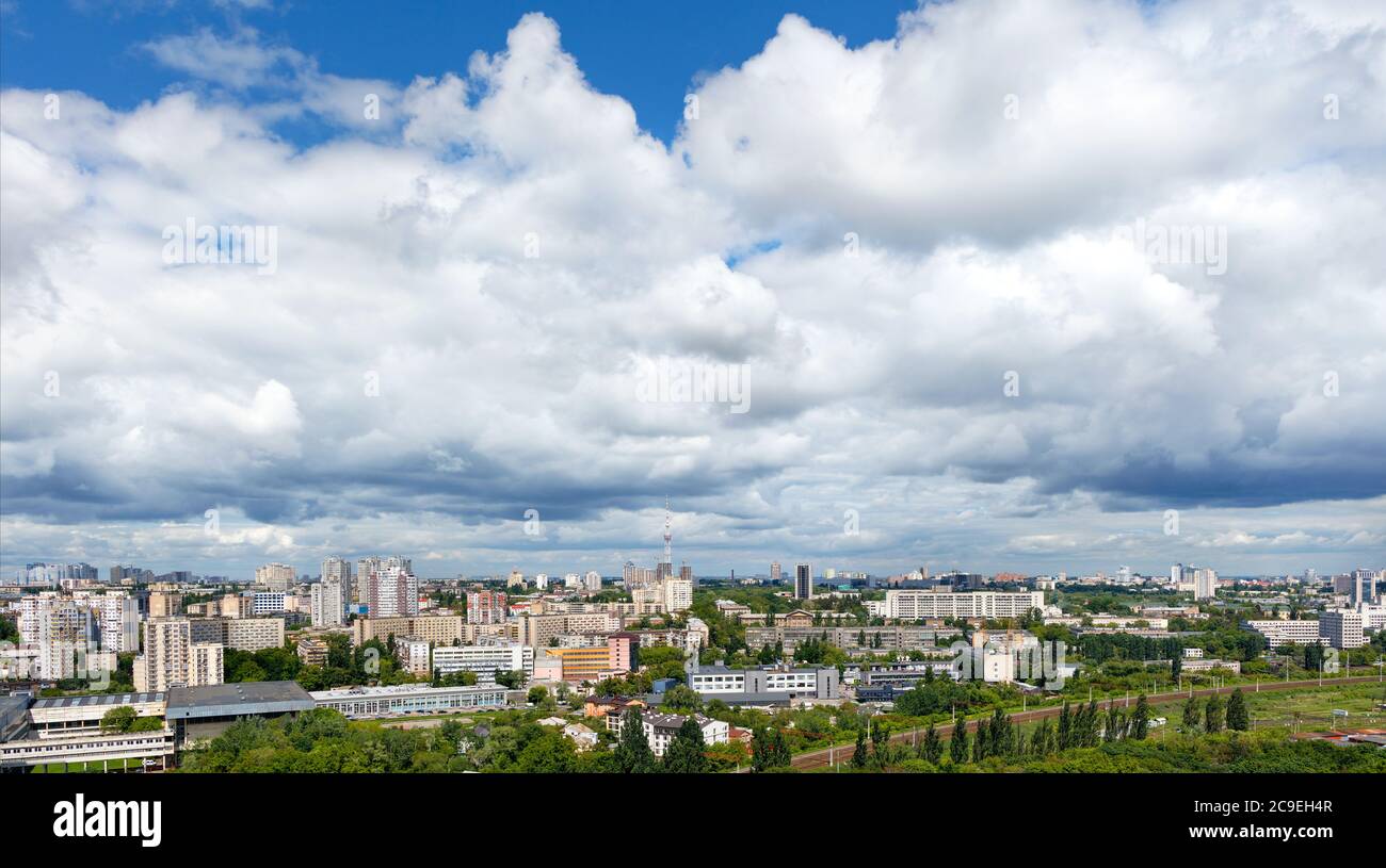 Große graue und weiße Wolken ragen über Kiews Wohngebieten, grünen Parks und einem Fernsehturm. Stockfoto