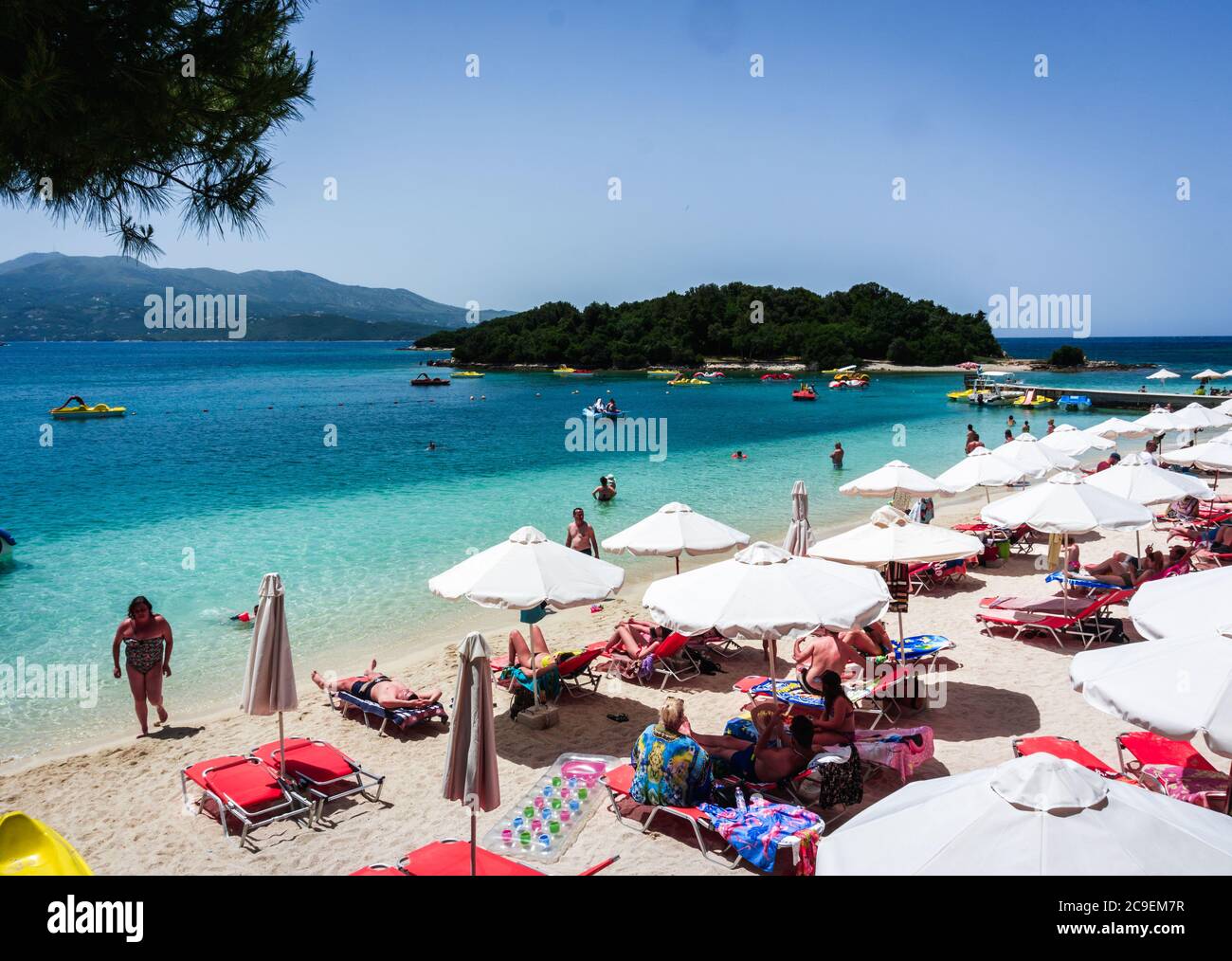 Einheimische und Touristen genießen einen sonnigen Tag am europäischen Sommer am schönen Strand von Ksamil in Sarande, Albanien. Stockfoto