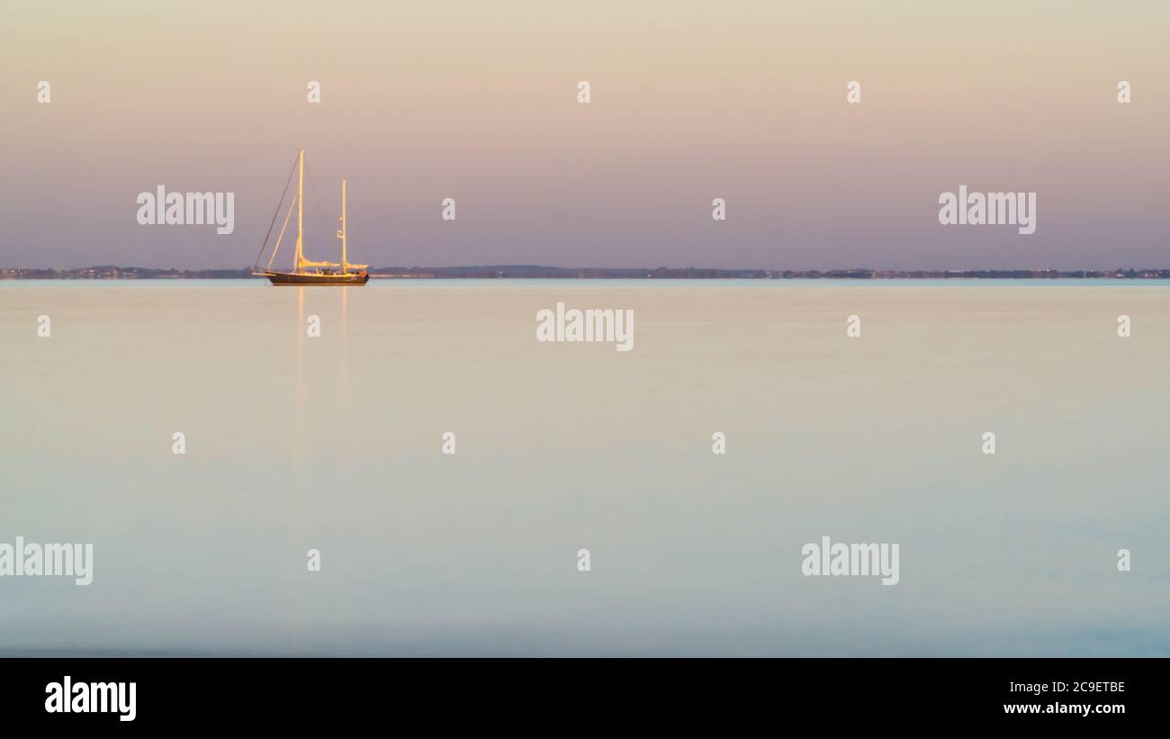 Segelboot, Insel Re, bei Sonnenuntergang auf einem sehr ruhigen Meer. Schöne minimalistische Seesee Stockfoto