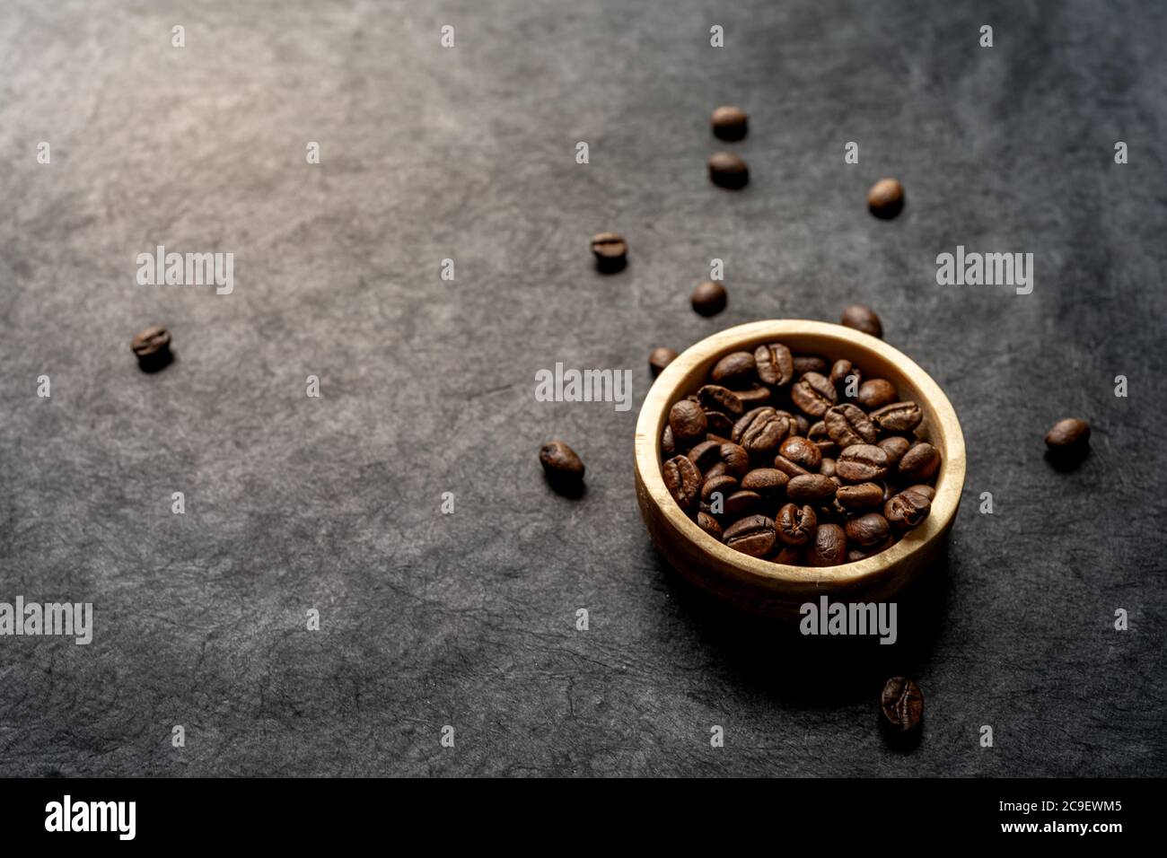 Nahaufnahme einer Holzschale gefüllt mit gerösteten Kaffeebohne auf dunklem Schieferhintergrund. Horizontales Format mit Platz für Text Stockfoto