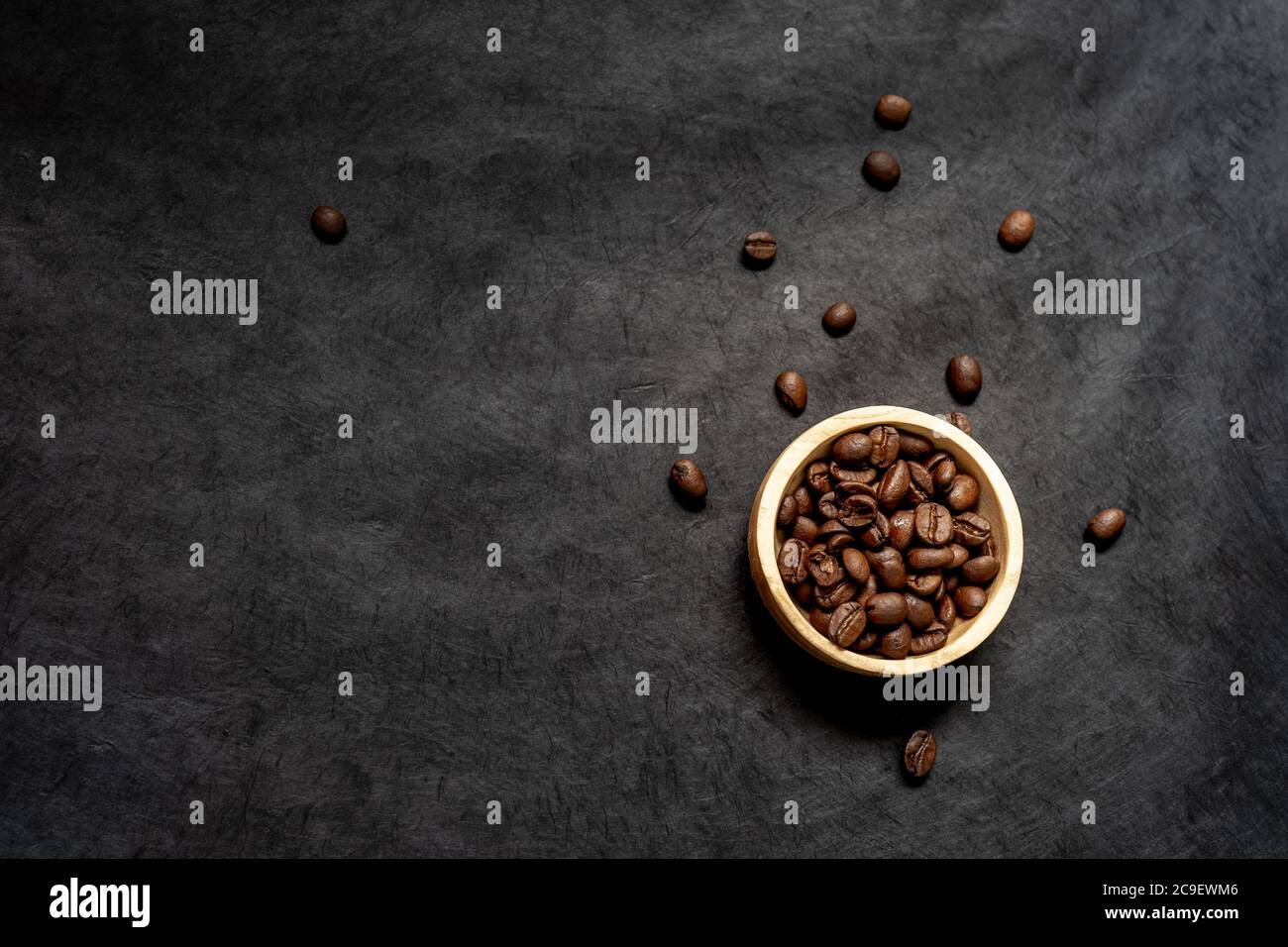 Draufsicht auf eine Holzschale gefüllt mit gerösteten Kaffeebohne auf einem dunklen Schieferhintergrund. Horizontales Format mit Platz für Text Stockfoto