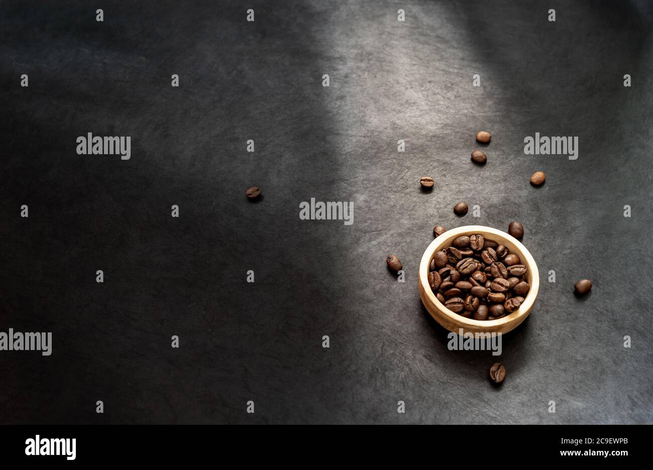 Nahaufnahme einer Holzschale gefüllt mit gerösteten Kaffeebohne auf dunklem Schieferhintergrund. Horizontales Format mit Platz für Text Stockfoto