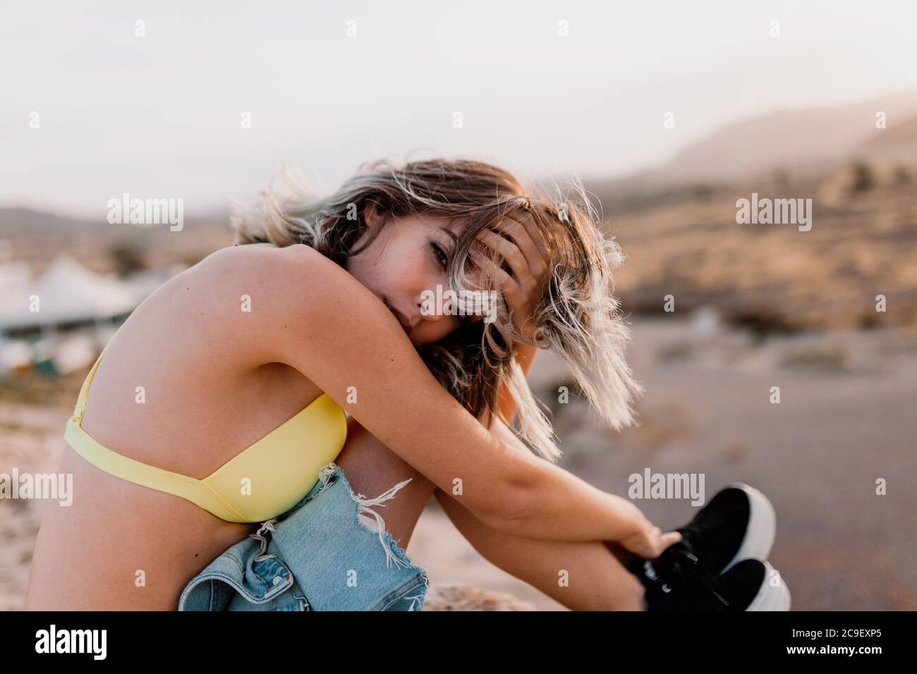Frau am Strand trägt gelben Badeanzug Stockfoto