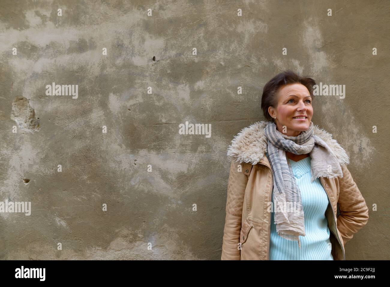 Glücklich reif schöne touristische Frau Denken gegen Betonwand im Freien Stockfoto