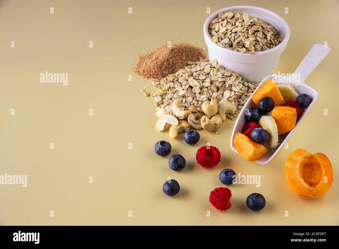 Frühstückszutaten für Müsli. Reife Früchte, Getreide, Milch, Nüsse und Samen. Stockfoto