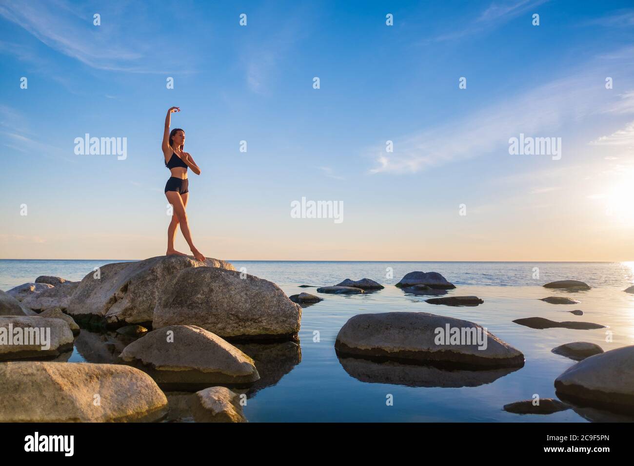 Anmutige Frau, die abends Yoga auf Stein macht Stockfoto