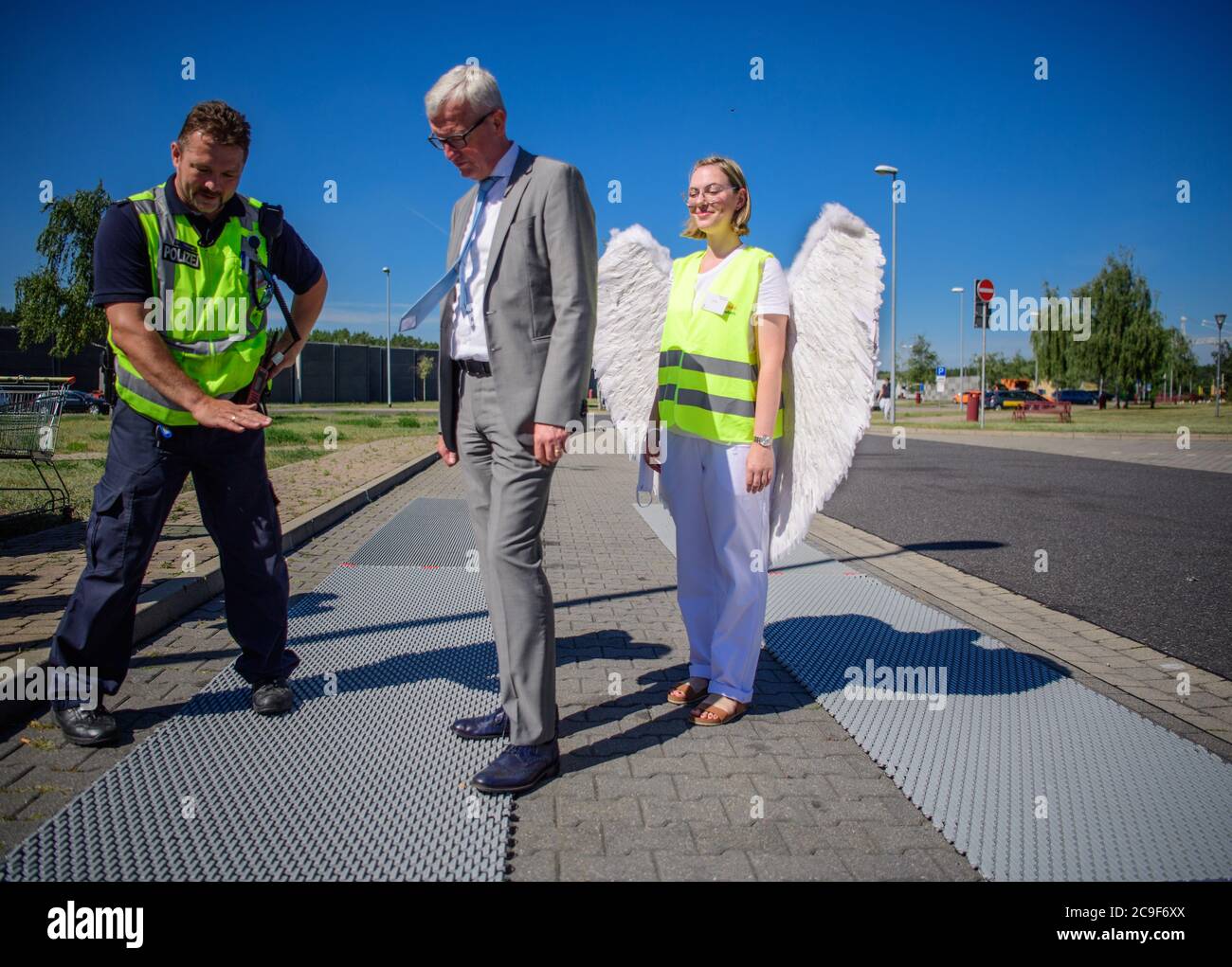 31. Juli 2020, Brandenburg, Michendorf: Guido Beermann (M, CDU), Brandenburgs Minister für Infrastruktur und Raumordnung, ist auf dem Gelände der Tankstelle Michendorf-Nord neben Emelie, bekleidet als Schutzengel Jo, Um sich über die Verkehrssicherheitskampagne 'lieber sicher - lieber leben' zu informieren und um Oberkommissar Falko Ditscher nach einer damit verbundenen Wägedienstleistung für Wohnmobile zu fragen. Im Rahmen eines Rundgangs durch alle brandenburgischen Autobahnrastgebiete sollen die Schutzengel und ihr Team die Fahrer vor allem während des Urlaubs für die Gefahren des Straßenverkehrs sensibilisieren Stockfoto