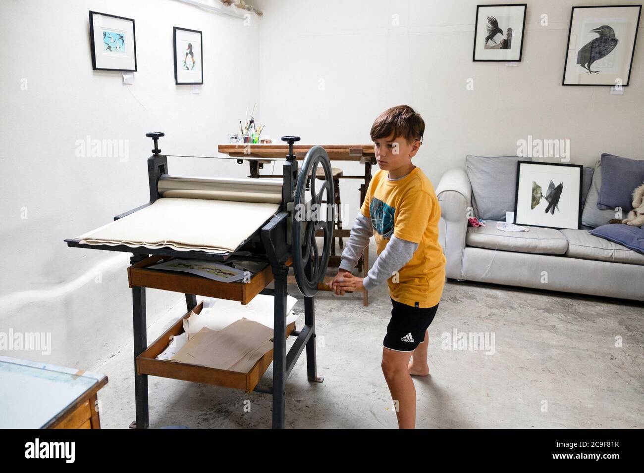 Boy Learning Printmaking in a Art Workshop Studio Drehen Sie das Rad auf einer Littlejohn Radierpresse in Carmarthenshire Wales UK KATHY DEWITT Stockfoto