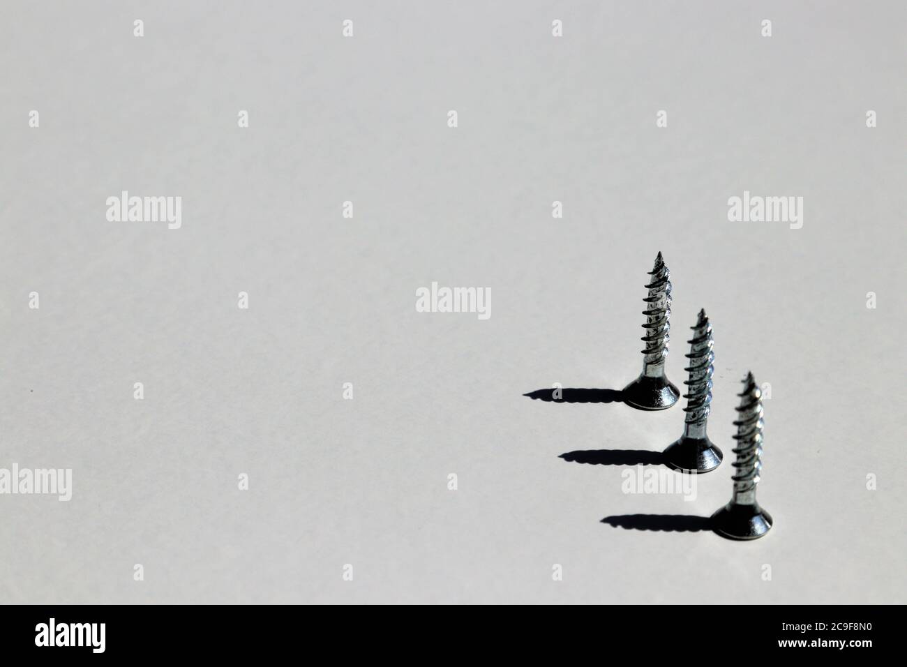 Drei umgedrehte Schrauben mit Schatten und weißem Hintergrund Stockfoto