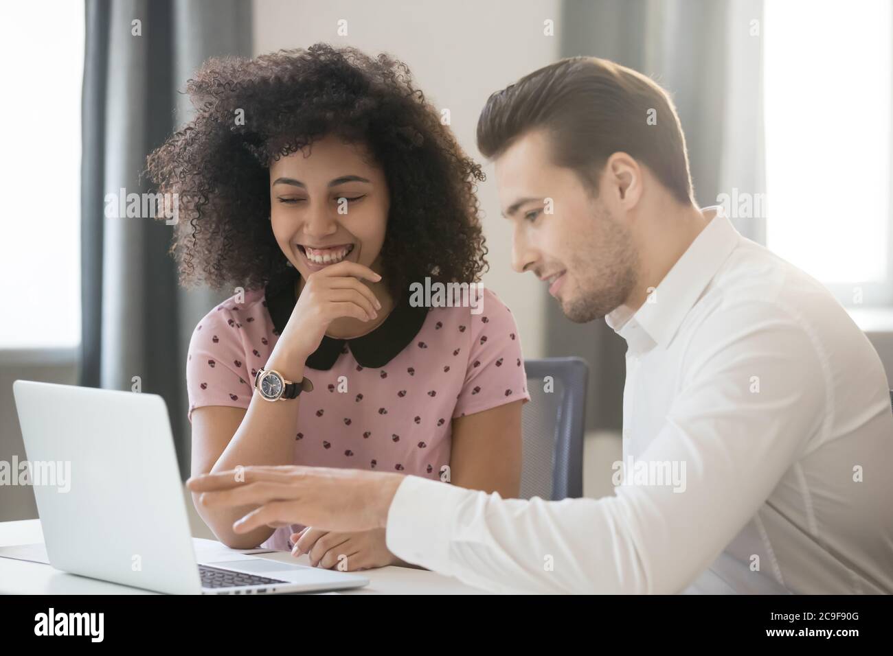 Verschiedene Kollegen arbeiten zusammen, nutzen Laptops und haben Spaß bei der Arbeit Stockfoto