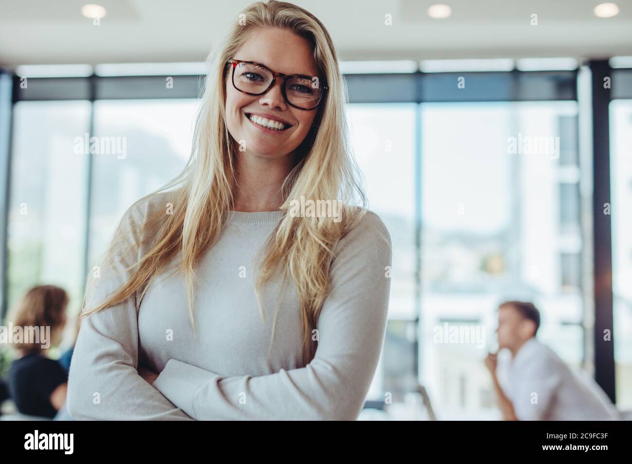 Porträt einer selbstbewussten Geschäftsfrau mit Kollegen im Sitzungssaal. Positive Frau mit Kollegen im Konferenzraum. Stockfoto