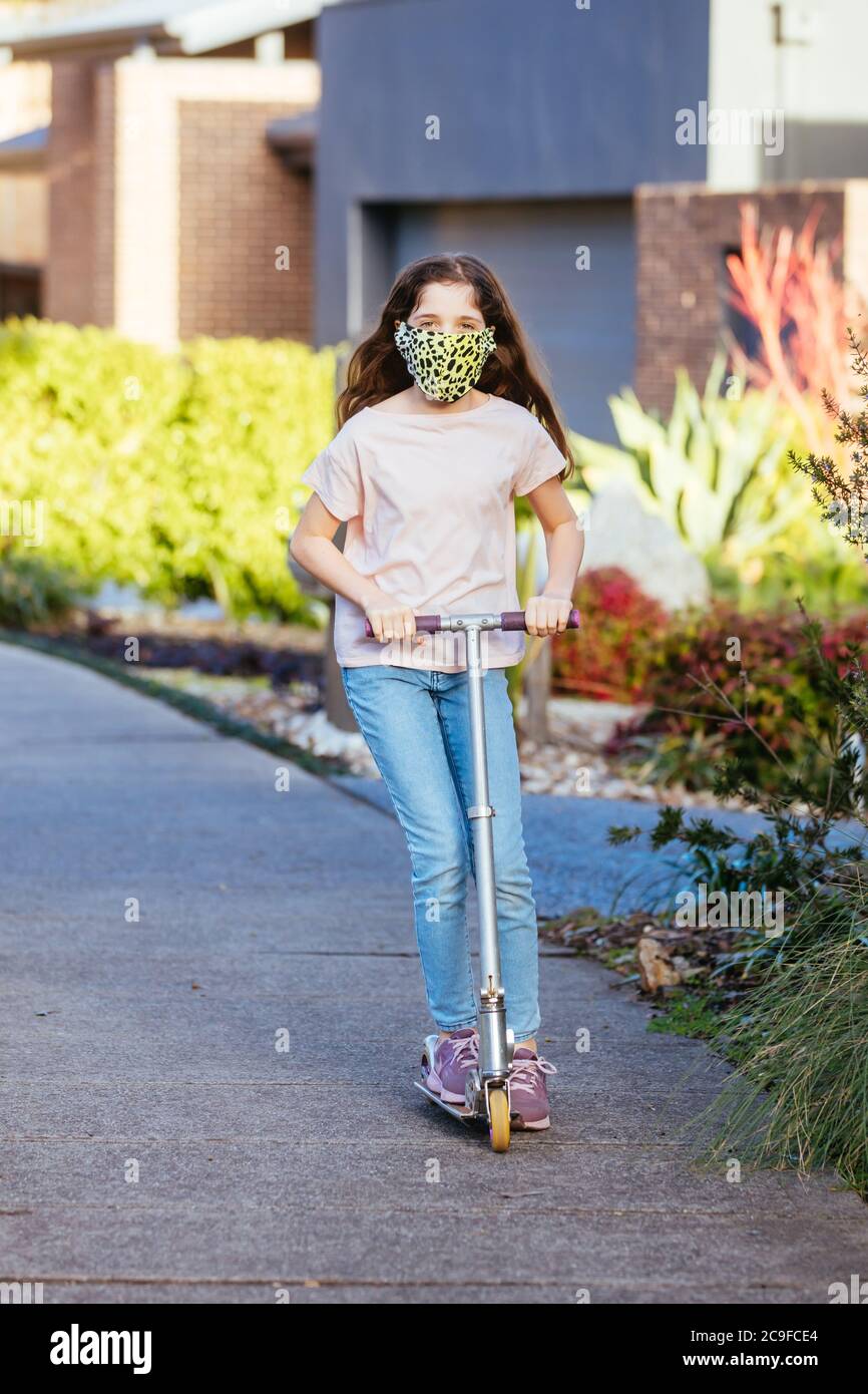 Mädchen spielt in der Straße mit Maske Stockfoto