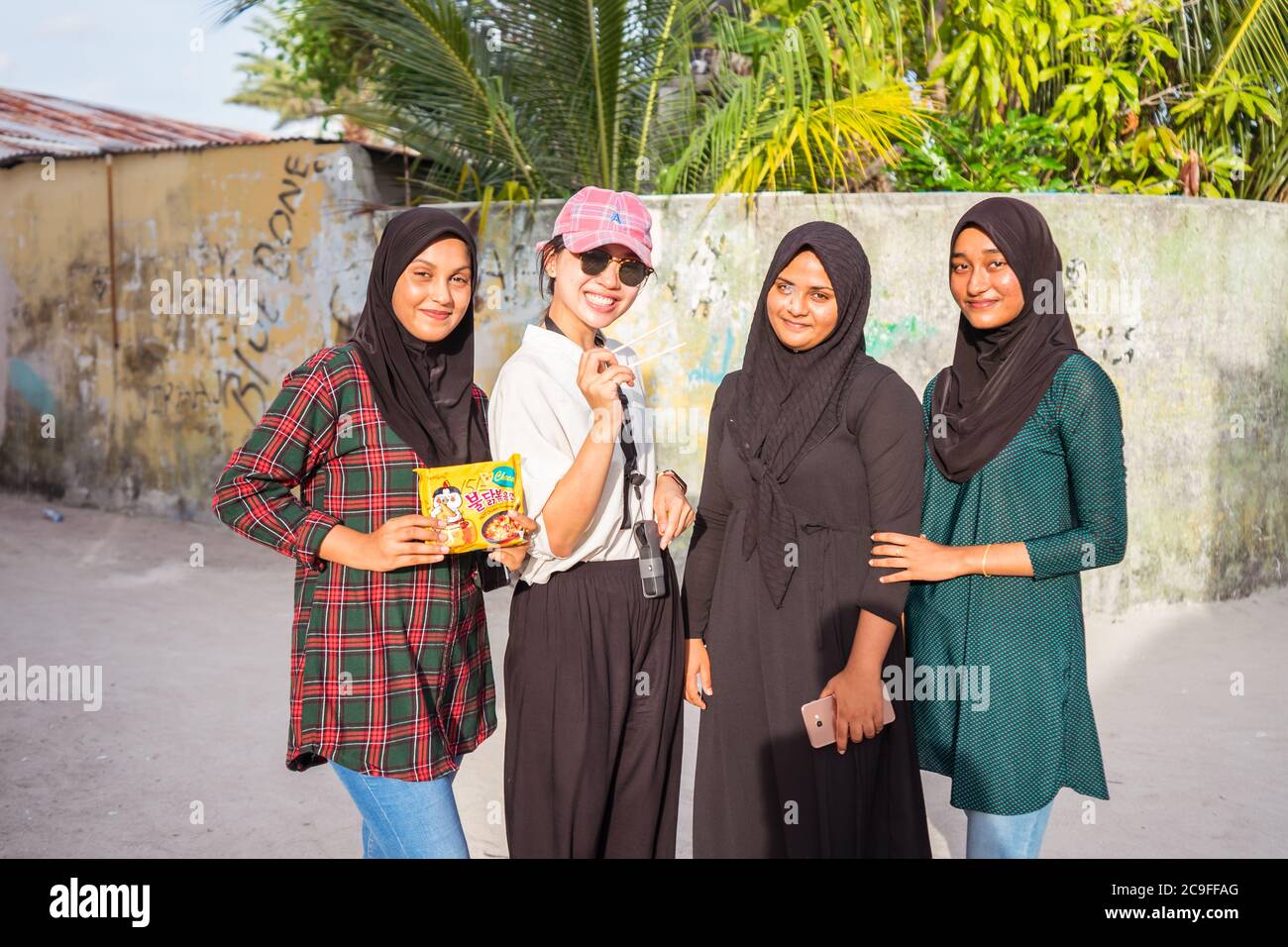 Bodufolhudhoo / Malediven - 17. August 2019: Junge Asiatin im Gespräch mit drei muslimischen einheimischen jungen Frauen mit schwarzem Hijab Stockfoto