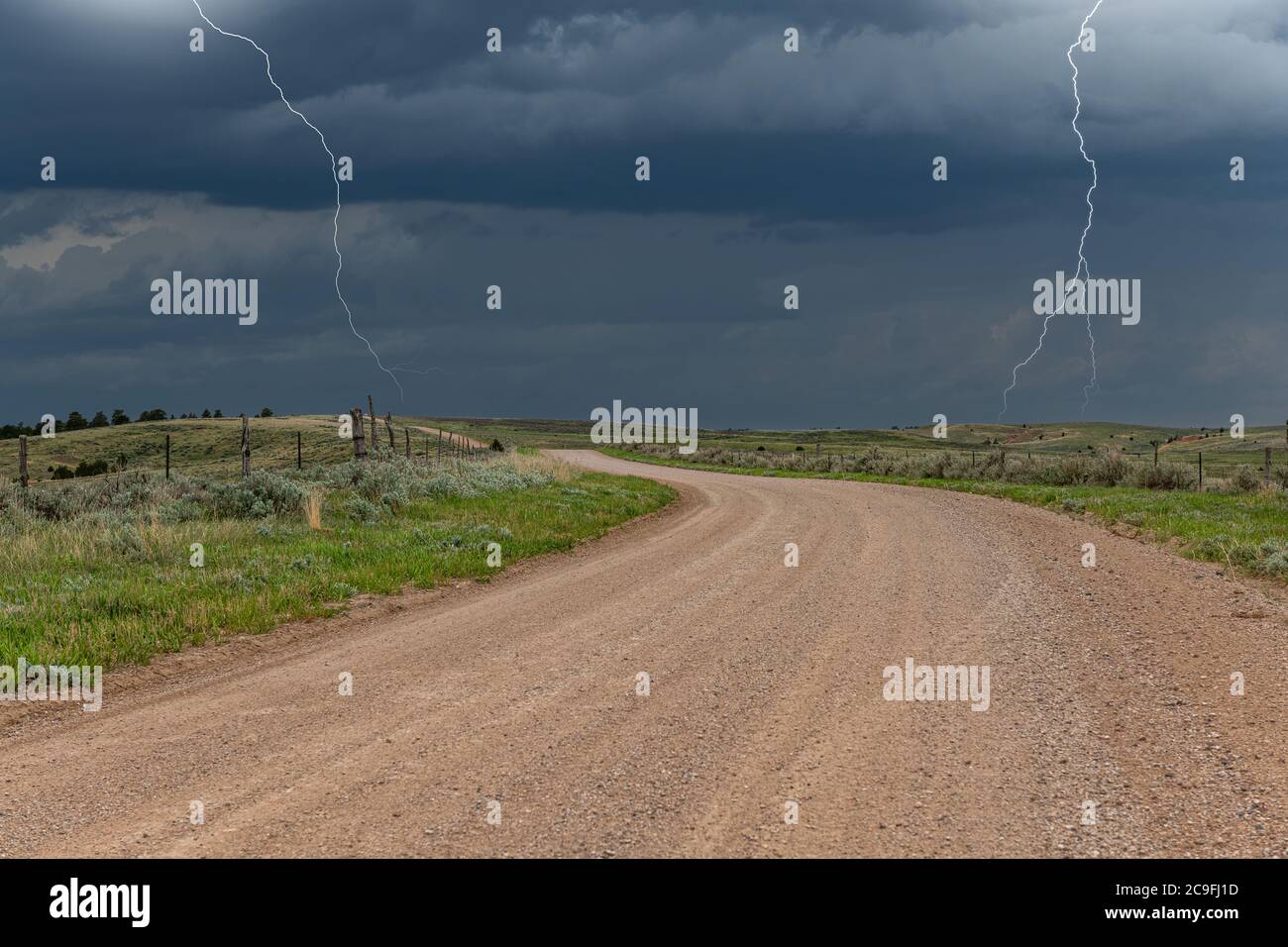 Wolke zu Boden Blitz hebt eine klassische Mittelwest Ackerland Feldweg und Weide, bevor ein massiver Regensturm entlädt über dem Land. Stockfoto