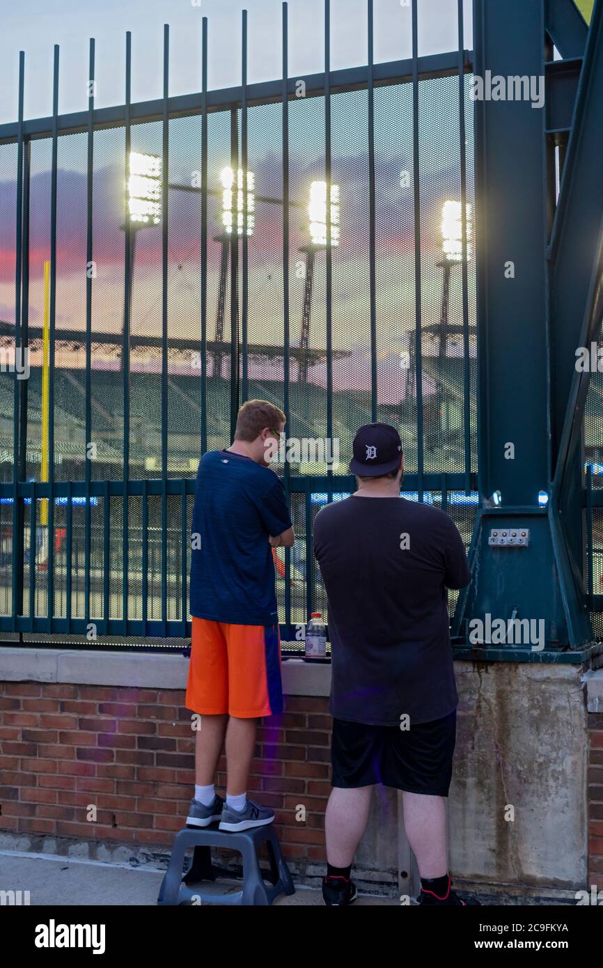 Detroit, Michigan, USA. Juli 2020. Baseball-Fans beobachten die Detroit Tigers spielen die Kansas City Royals durch einen Zaun im Comerica Park. Zuschauern ist es aufgrund der Coronavirus-Pandemie untersagt, das Stadion zu betreten. Kredit: Jim West/Alamy Live Nachrichten Stockfoto