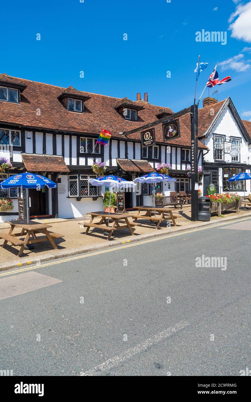 Das Queens Head Pub bei Sommersonne. Tische und Bänke mit Sonnenschirmen stehen auf dem Bürgersteig. High Street, Pinner, Middlesex, England, Großbritannien Stockfoto