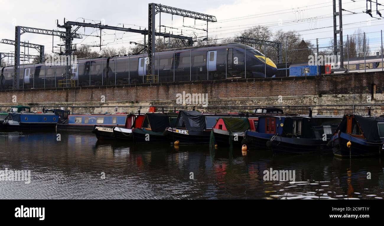 Ein Javelin-Zug fährt an den im Regent's Canal verankerten Kanalbooten vorbei, wenn er den Bahnhof Saint Pancras in London verlässt Stockfoto
