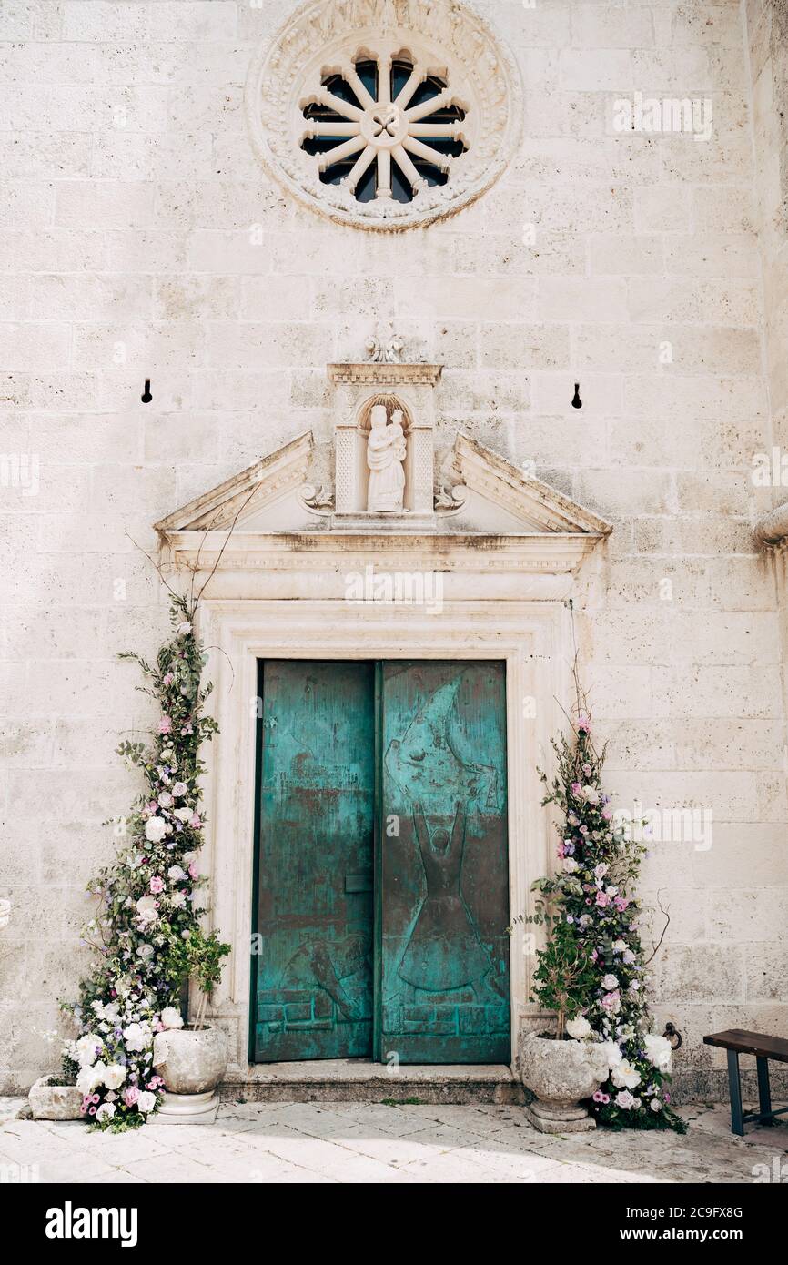 Die Türen zur Kirche sind grün mit Mustern, geschmückt mit Blumen und göttlichen Symbolen. Insel Gospa od Skrpella in Perast, Montenegro. Stockfoto