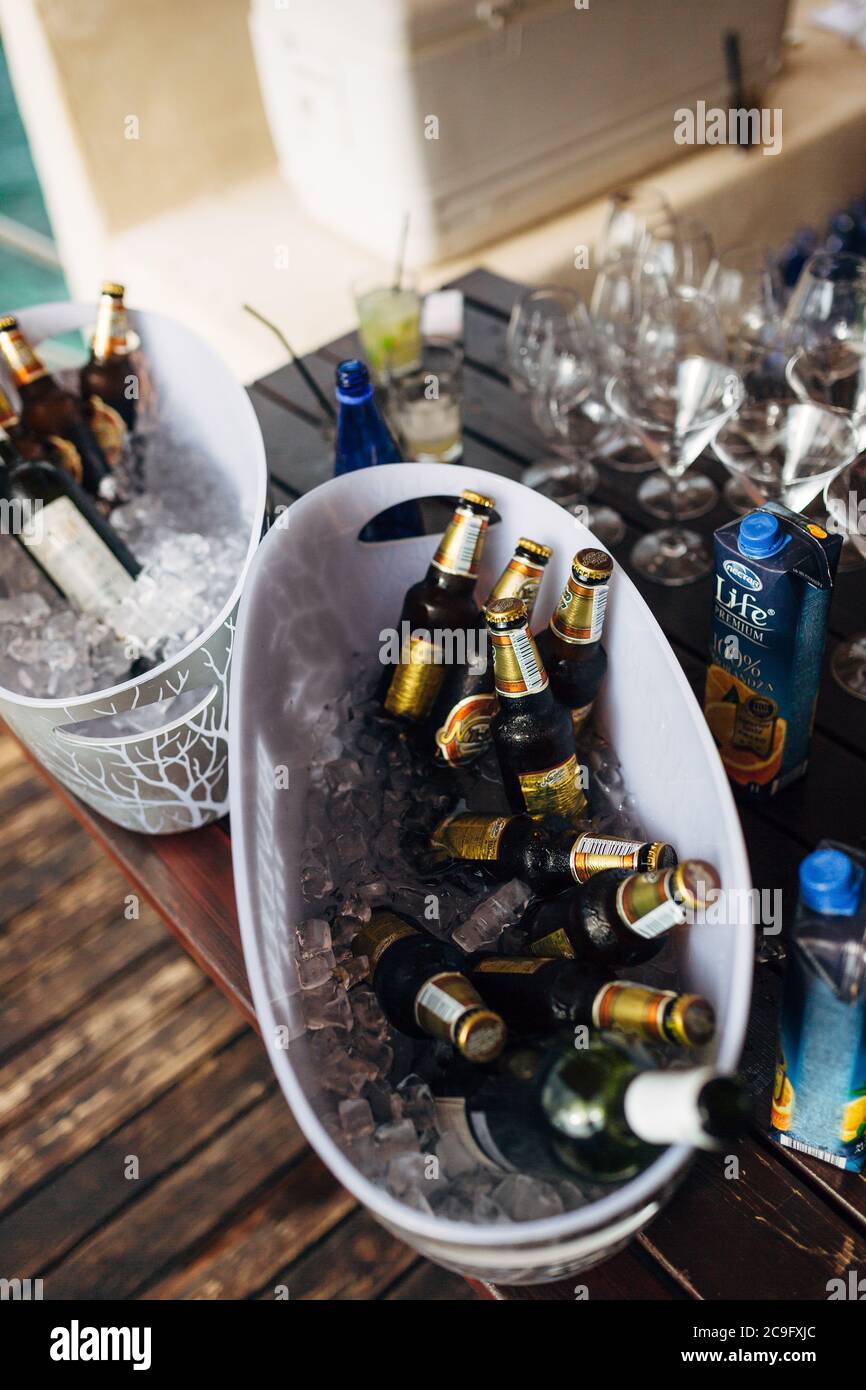 Zwei Eiskübel voller Bierflaschen für eine Party auf einem Holztisch mit leeren martinigläsern und Saftdosen. Stockfoto