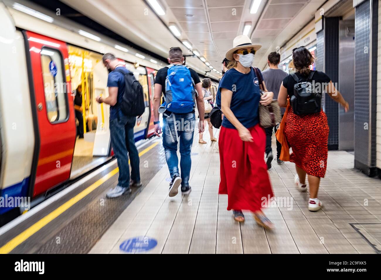 London - Juli 2020: Pendler auf einem Bahnsteig der Londoner U-Bahn mit Covid 19 Gesichtsmasken Stockfoto