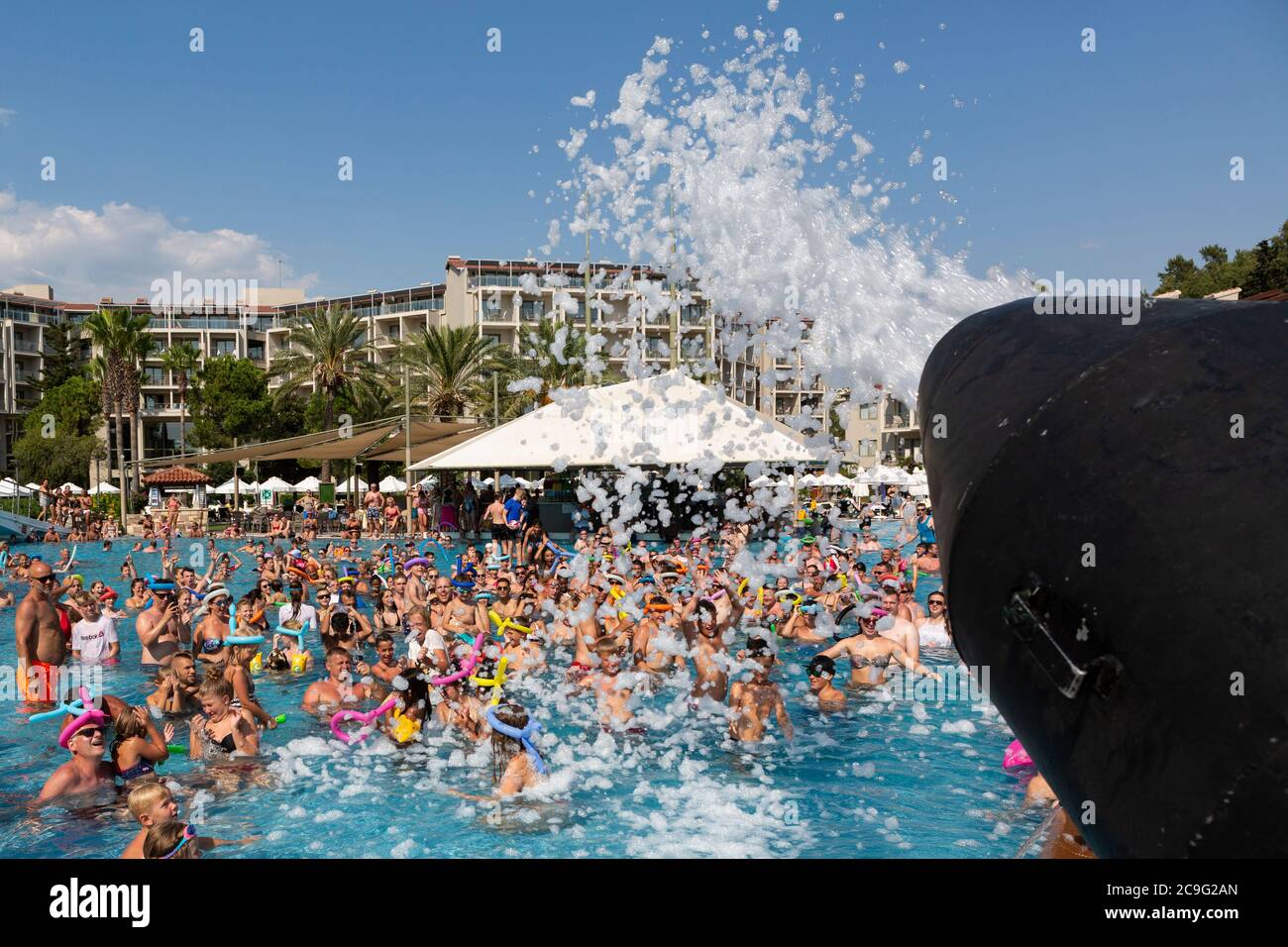 Bei einer Schaumparty wird Schaum auf Personen in einem Schwimmbad aufgesprüht. Stockfoto