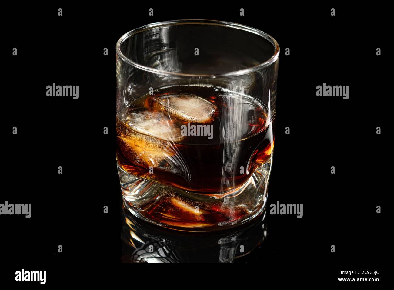 Glas mit Whiskey und zwei Eiswürfeln auf schwarzem Hintergrund Stockfoto
