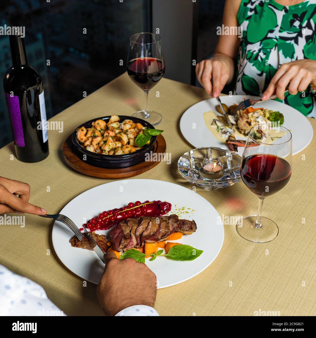 Pärchen beim Abendessen, Steak, Meeresfrüchte und Wein Stockfoto