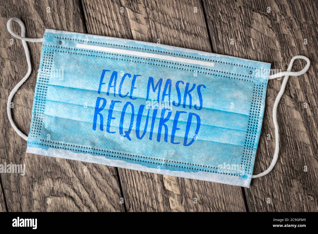 Gesichtsmasken erforderlich - Text auf einer Einweg-Maske, Geschäftszeichen während der Coronavirus covid-19 Pandemie und soziale Distanzierung Stockfoto