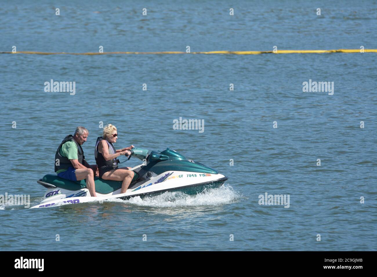 Zwei Senioren - ein Mann und eine Frau fahren zusammen einen Jet-Ski - Oma fährt und Großvater ist auf dem Rücksitz fahren Pilotierung der Ski auf Clearlake Stockfoto