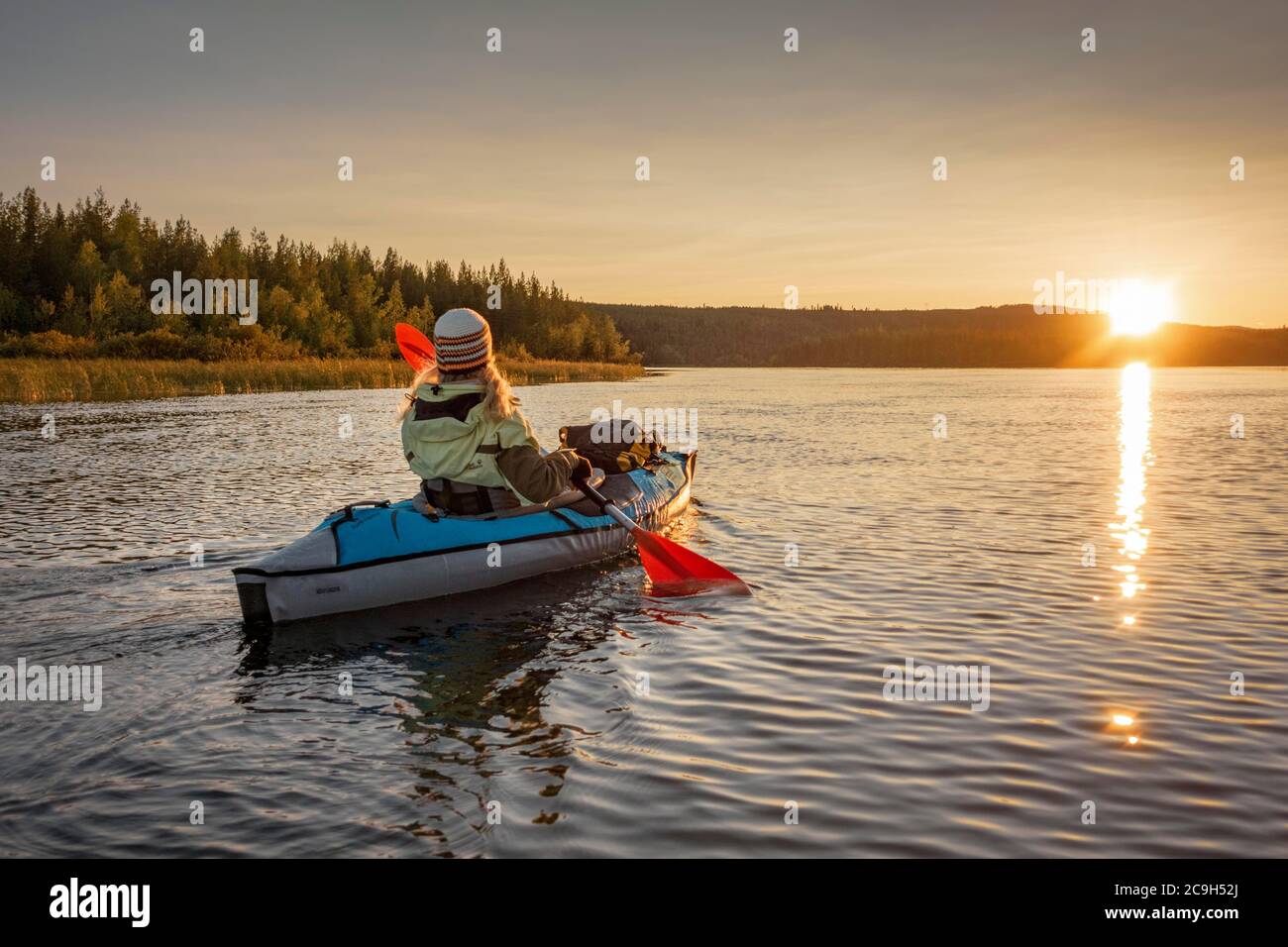 Kayaker, Ende 40er Jahre, blond, Paddel mit aufblasbarem Kajak bei Sonnenuntergang auf einem See in Abendstimmung, Muddus National Park, Jokkmokk, Norrbottens laen Stockfoto