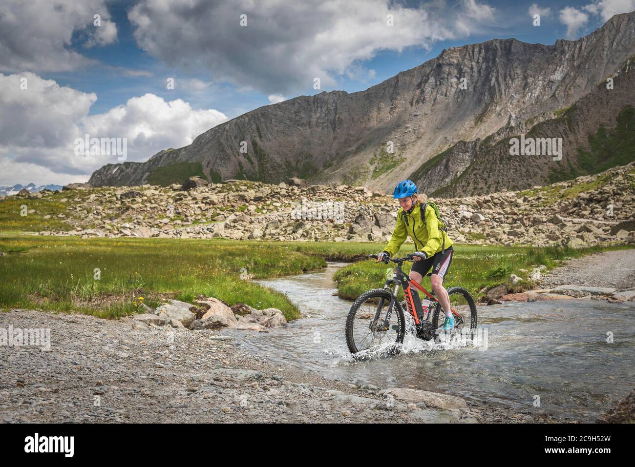 Mountainbiker fahren auf alpiner Schotterstraße durch Bergfluss, Serfaus, Tirol, Österreich Stockfoto