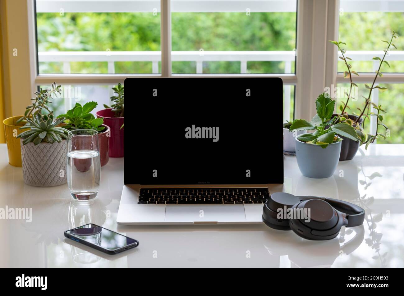 Home Office mit Laptop, Apple MacBook Pro und iPhone X mit Kopfhörer am Schreibtisch, mit schwarzem Bildschirm, München, Deutschland Stockfoto