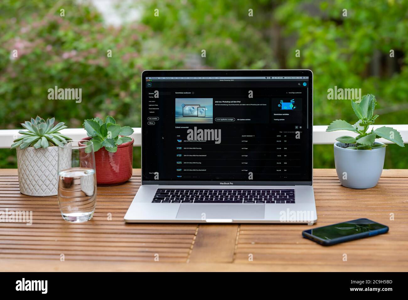 Home Office mit Laptop, Apple MacBook Pro mit iPhone X am Schreibtisch, mit Adobe Photoshop-Anwendung beim Bearbeiten von Fotos, Deutschland Stockfoto