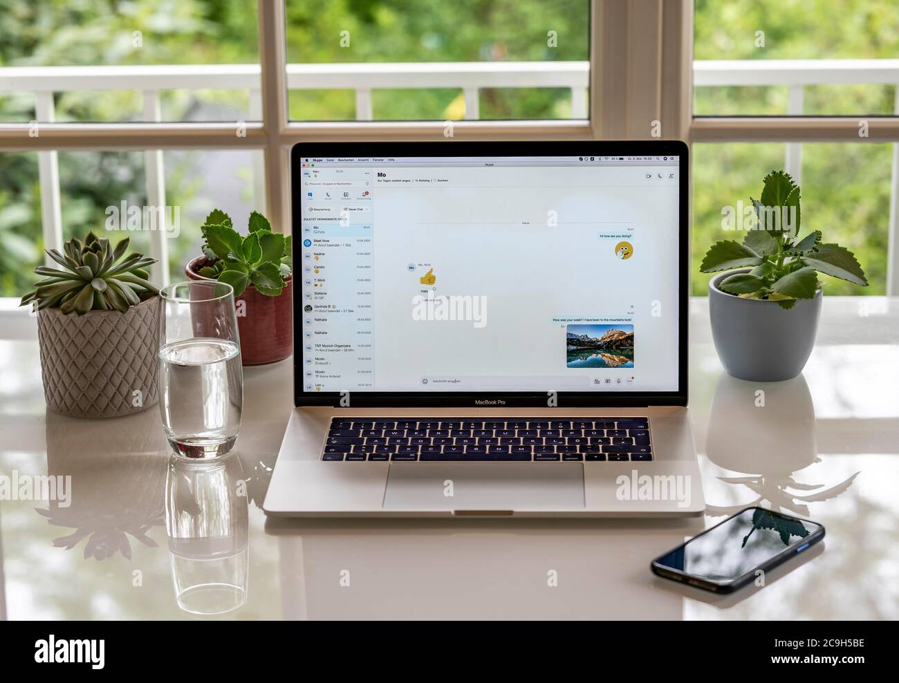 Home Office mit Laptop, Apple MacBook Pro mit iPhone X am Schreibtisch, mit offenem Chat-Fenster im Skype Messenger Service, München, Deutschland Stockfoto
