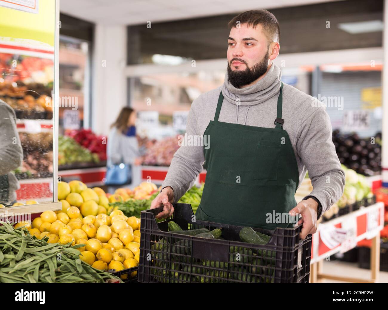 Positive Verkäufer in Schürze arbeiten in Gemüsemarkt Stockfoto