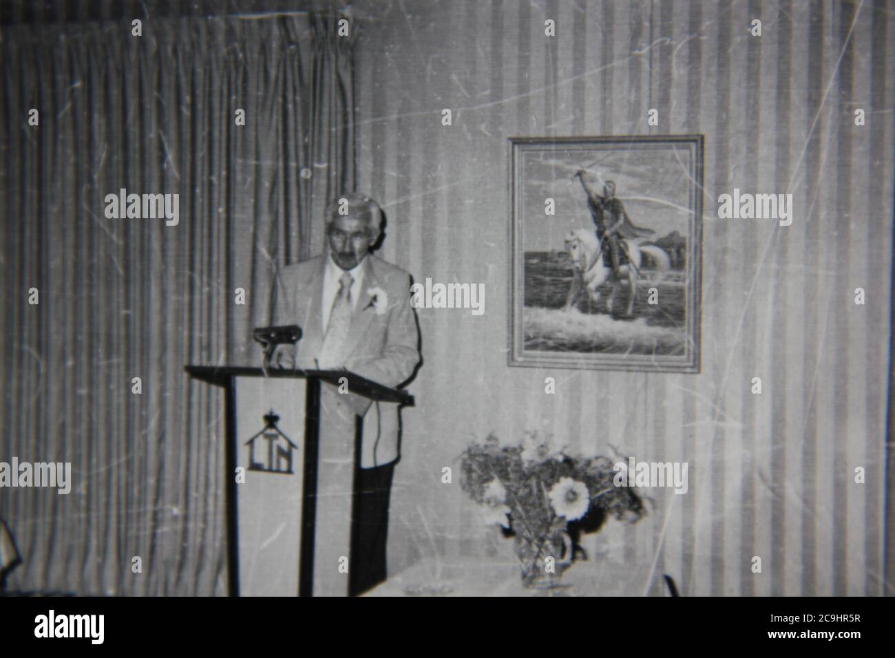 Feine Vintage-Schwarz-Weiß-Fotografie eines erwachsenen Sprechers aus den 1970er Jahren, der auf dem Podium referiert. Stockfoto
