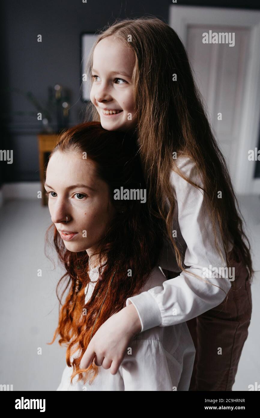 Yong und Erwachsene Schwestern umarmen sich im Loft, die Freundschaft, Vertrauen, Ähnlichkeit repräsentieren Stockfoto