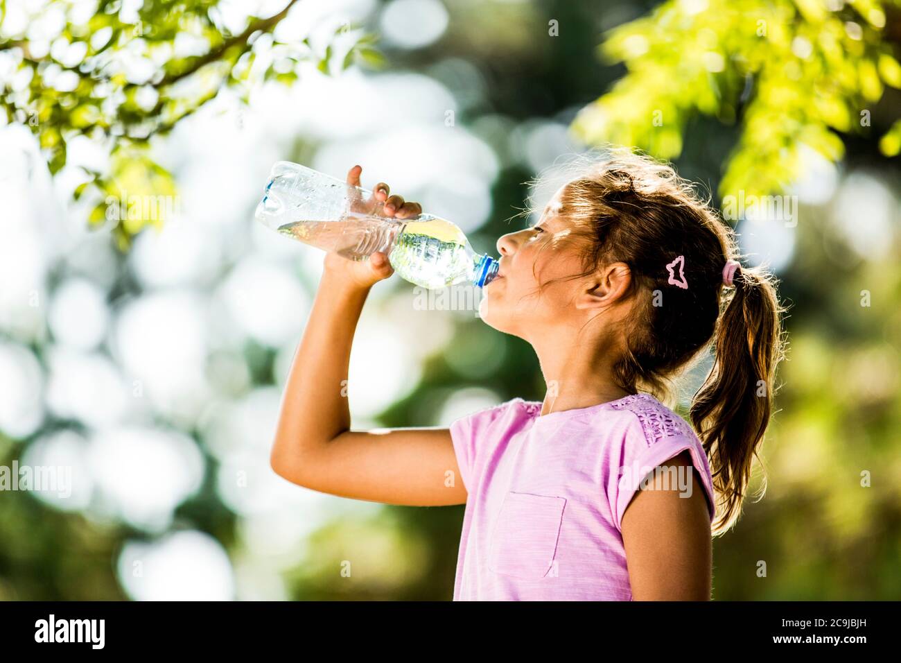 Mädchen Trinkwasser aus Plastikflasche im Park. Stockfoto