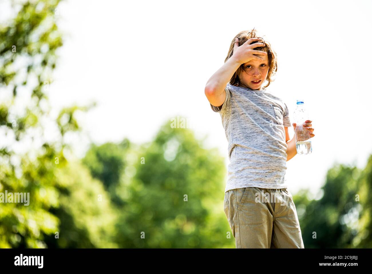 Junge hält Wasserflasche im Park, Porträt. Stockfoto