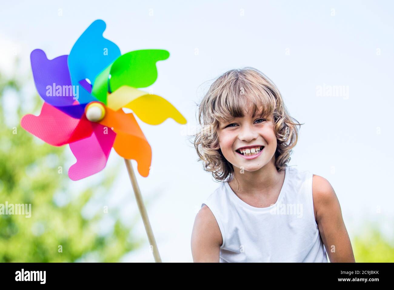 Junge hält Papierwindmühle und lächelt. Stockfoto