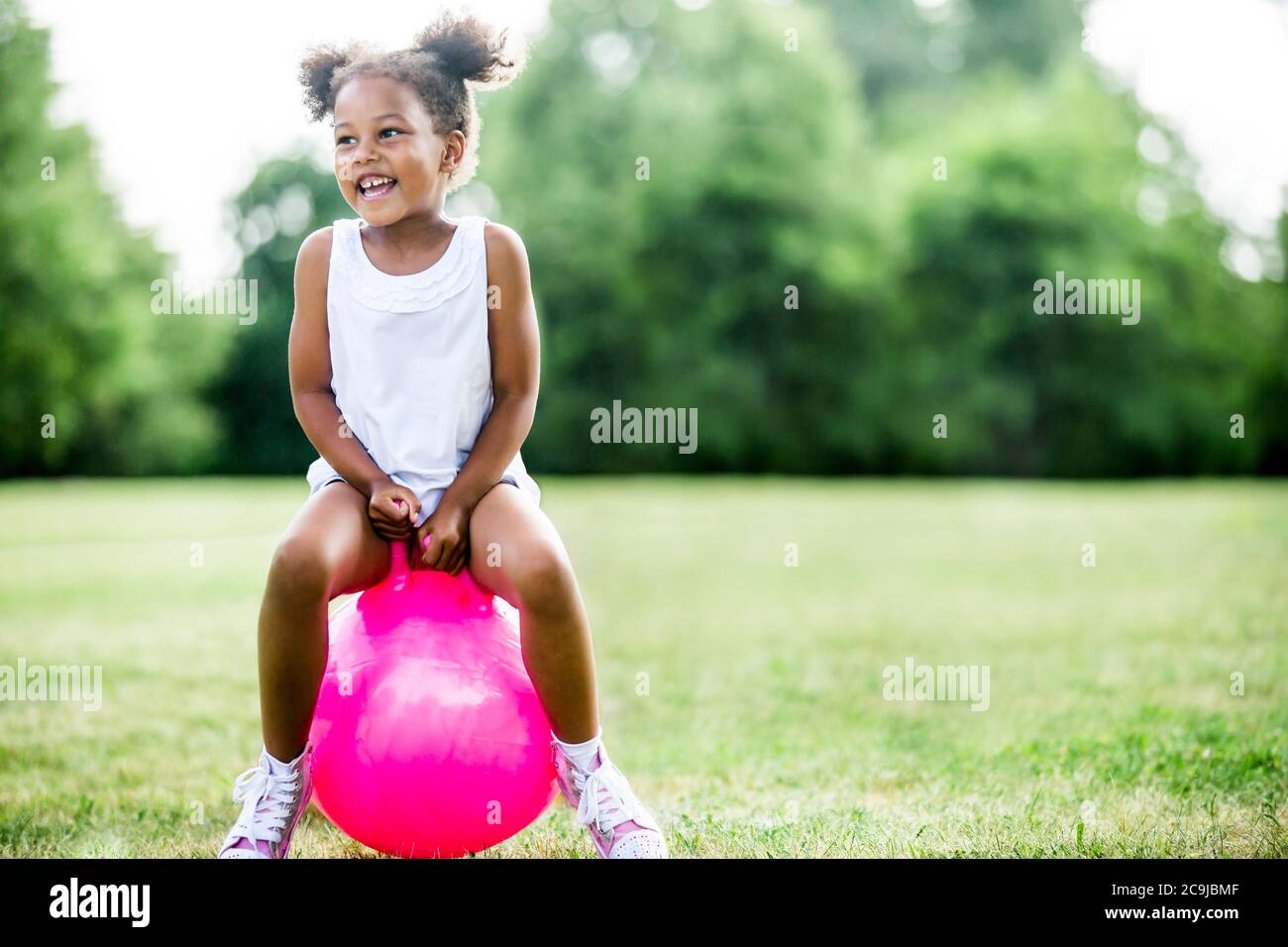 Mädchen hüpft auf aufblasbaren Trichter im Park, lachen. Stockfoto