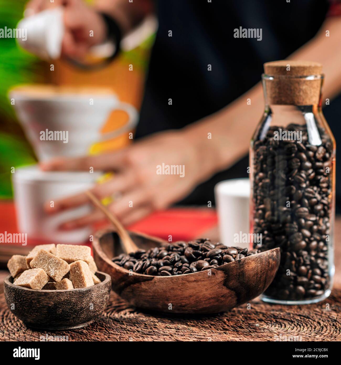 Kaffeebohnen in Holzschüssel. Filterkaffee mit manuellem Kaffeetropfer im Hintergrund zubereiten. Stockfoto